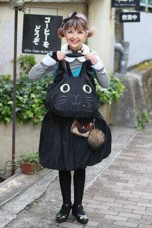 お手製のぬいぐるみや小物を身につけ、本日は全身黒猫風コーディネート！　お気に入りの喫茶店の前で。　撮影／坂本利幸