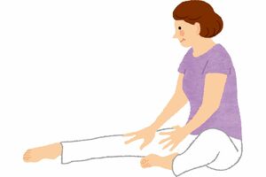 やさしい“カエル体操”　(1)床に座って、片足を前にまっすぐ伸ばす。もう片方の足は、膝を曲げて内側に折る。
