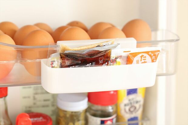【H】小袋は専用ケースに入るだけの量に。タレやカラシなどの小袋調味料は、専用ケースにまとめ、入りきるだけ保存を。「ケースは100均に売っています。フック付きなので、卵の棚などにつければ使いやすい！」