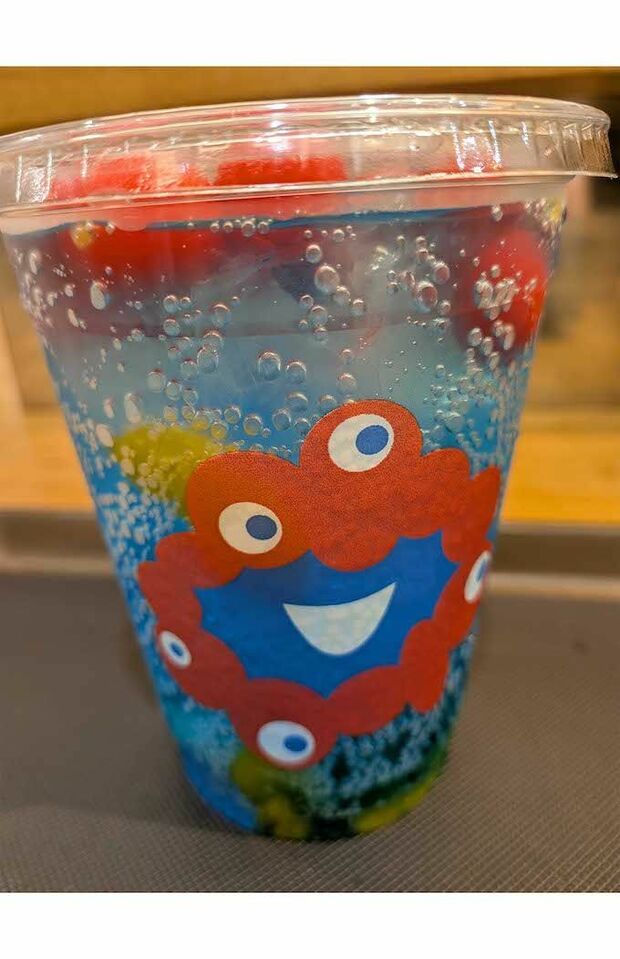 エスタシオンカフェにて販売されている『ミャクミャクフルーツソーダ』。青いソーダに真っ赤なチェリーが浮かぶ(Xより)