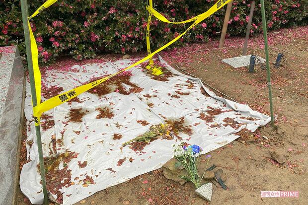 墓地脇の遺棄現場にはシートがかけられ、花が手向けられていた