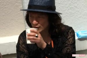 座ってカップを手にするユカイ（'18年5月）