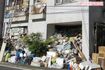 ガレージのゴミは敷地外の歩道にもいまだにはみ出し、通行の妨げになっている