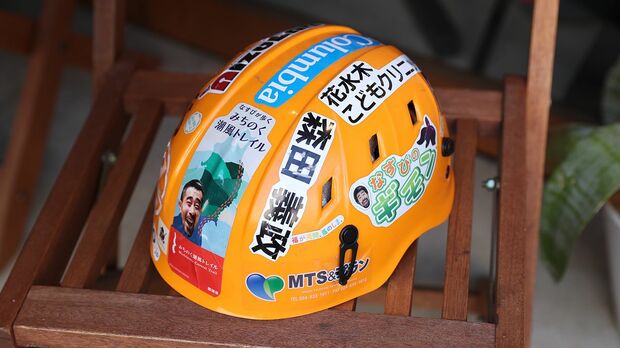 支援者のステッカーを貼ったヘルメットとともに山頂に