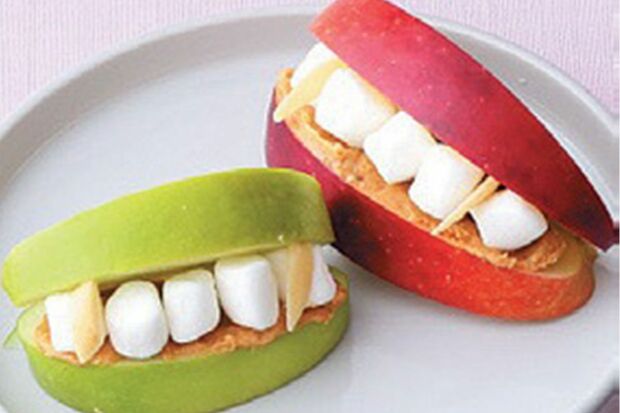 【ドラキュラの入れ歯】りんごにピーナツバターを塗り、ミニマシュマロをサンドしたら完成。りんごは厚さ1．5cmぐらいに切るとバランスがいい。牙の形に切ったアーモンドをさして雰囲気アップ。　『可愛くって ホラーで 美味しい！ キモめし』より