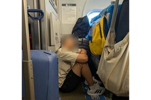 本来荷物を置くスペースのはずが…地べたで体育座りをする外国人旅行客とみられる男性(Xのユーザーより)