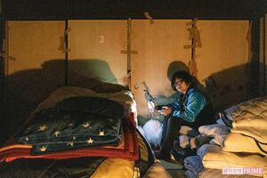 開かずの間の前で生配信を行う松原さん。滞在中、熟睡していた猛者もいるという