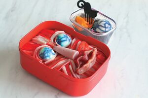 【顔面筋肉のお弁当】細かく裂いたかに風味かまぼこで筋肉っぽさを表現したお弁当。お弁当箱にごはんを詰め、目、鼻、口部分をへこませ、かに風味かまぼこを筋肉のようにのせる。目にうずら卵、鼻に魚肉ソーセージ、唇に生ハムを使用した。　『可愛くって ホラーで 美味しい！ キモめし』より