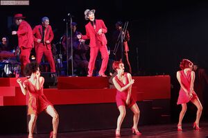 真っ赤なスーツに身を包み、軽快なステップを踏みながらセクシーな美女たちと歌って、踊る!　撮影／佐藤靖彦