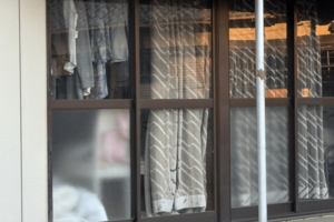 つくば市内の容疑者宅の窓辺は、カーテンやつるした衣服などで目隠しされていた