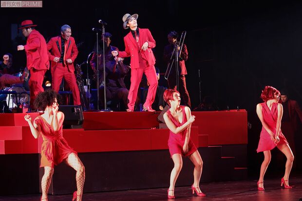 真っ赤なスーツに身を包み、軽快なステップを踏みながらセクシーな美女たちと歌って、踊る!　撮影／佐藤靖彦