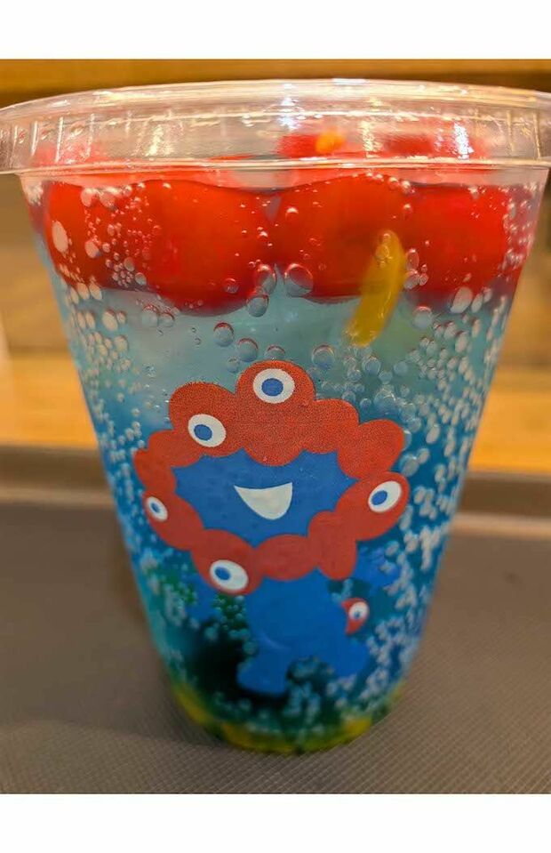 エスタシオンカフェにて販売されている『ミャクミャクフルーツソーダ』。青いソーダに真っ赤なチェリーが浮かぶ(Xより)