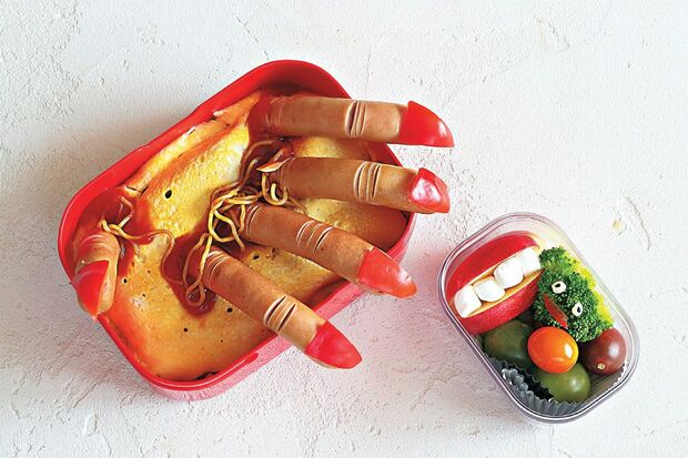 【指ウインナーのオムそば弁当】指はウインナー、爪はミニトマトの果肉で作ったもの。ウインナーに関節に見立てた切り込みを入れるとリアル。焼きそばを薄焼き卵で包んだオムそばを作る。薄焼き卵に切れ込みを入れ、指ウインナーを5本差し込んだら完成。　『可愛くって ホラーで 美味しい！ キモめし』より