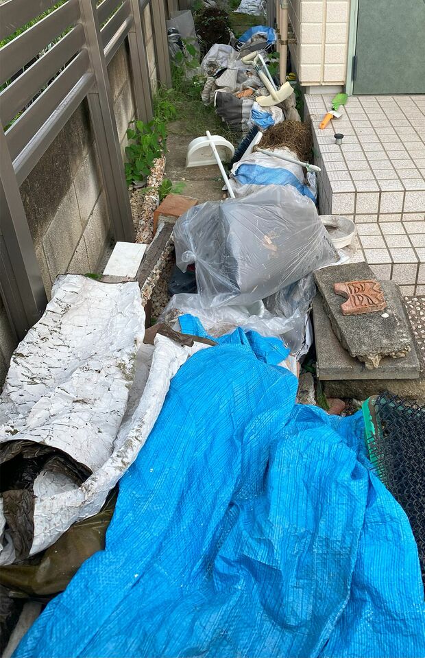 自宅裏に枯れ草やビニール袋、スコップなどが乱雑に放置されていた