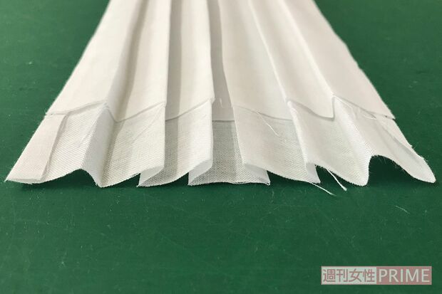 (4)プリーツをたたむ。上下に二つ折りにしてアイロンをかけ、真ん中に折り目をつけてから、そこに向かって写真のようにたたむ。たたむ幅は7mm～1cmくらいの間で適当でOK。折り目はアイロンでひとつずつしっかり押さえながらつけるとやりやすい。