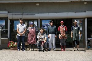 お店をバックに、マネージャー役の工藤さん（左）、菊谷さん夫婦（中央）とお店のスタッフ。その場で焼いて食べるイカは最高に美味と評判　撮影／竹内摩耶