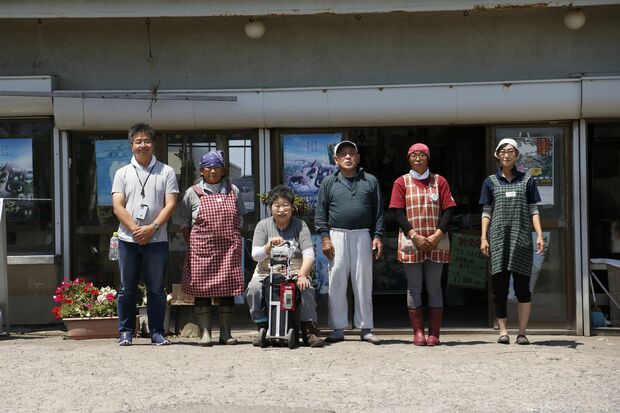 お店をバックに、マネージャー役の工藤さん（左）、菊谷さん夫婦（中央）とお店のスタッフ。その場で焼いて食べるイカは最高に美味と評判　撮影／竹内摩耶