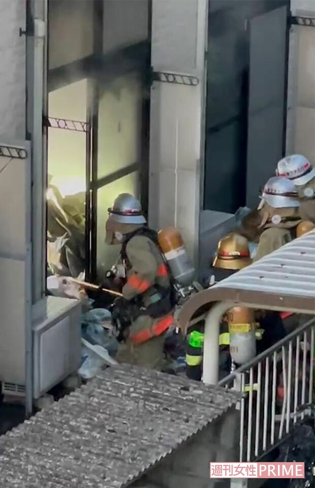 裏手の窓ガラスを割り、田原春貴之容疑者の部屋のゴミを熊手のような棒で掻き出す消防隊員（目撃者提供）