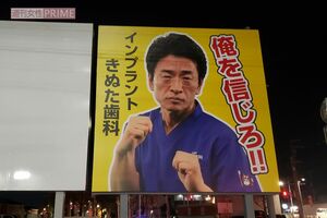 『きぬた歯科』看板マニアが260箇所から選ぶ「オススメ看板3選」その3 「立川市北西部、玉川上水にかかる橋のたもとにあります。かつては違ったデザインの看板でしたが、太陽にさらされ色あせてしまい、昨年リニューアルを実行しました。掲げられたポーズは、格闘技イベント『RIZIN』でのキャンペーンに伴い撮影されたものですが、Twitterで“これを看板に載せたら？”という声が上がり実現しました。これと同じデザインの看板は、他にも8か所見られます」（『看板研究家』D.J.マメ氏）