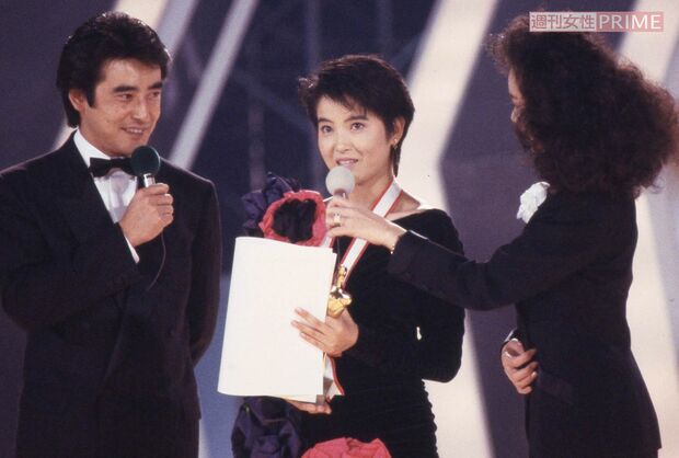 1987年の『全日本歌謡音楽祭』にて受賞の喜びを語る荻野目洋子。大判の赤い花が目立つ衣装も似合う