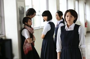 清野菜名の初主演映画『東京無国籍少女』、校内をフラフラと歩く藍に視線を送る教師と同級生たち。事故がきっかけで心身に傷を負った藍（清野菜名）は〝何かがおかしい〟と違和感を覚えながら学園生活を送っている。その謎が明らかになる衝撃的なラスト15分は必見!　押井監督が描く展開と清野菜名の活躍をお楽しみに。7月25日（土）より新宿バルト9ほか全国ロードショー© 2015東映ビデオ