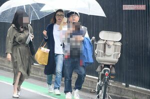 第3子を田中が抱き、肩を並べて歩くペアルックの田中、山口夫妻