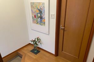 靴箱をなくしたスペースには大きめの絵と、床には季節の花を飾る。今はあまり使っていなかった廊下の収納棚を靴入れに使用