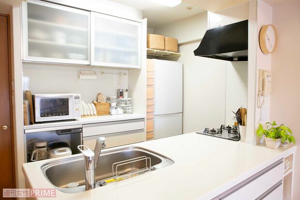 キッチンボードのつり戸棚の右側は乾物類、左側によく使う食器類を。冷蔵庫横の収納ボックスには目線から下には缶詰やストック食品など、目線より上には使用頻度の低いキッチン掃除用品が入っている　撮影／伊藤和幸