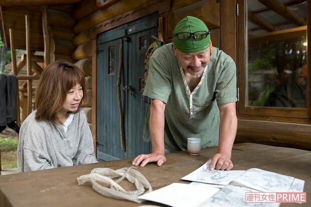 アイデアスケッチの前でキミさんと。漫画家としての資質が図面を引かずに家を造る一助となった。机の上にはアオダイショウの抜け殻も　撮影／伊藤和幸