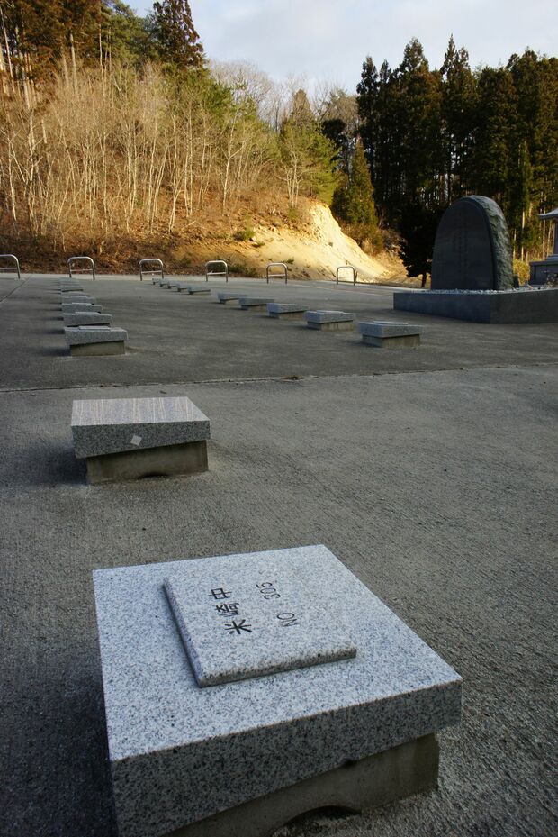墓石には遺体安置所と番号。隣は引き取られて名板がない＝岩手県陸前高田市・普門寺で