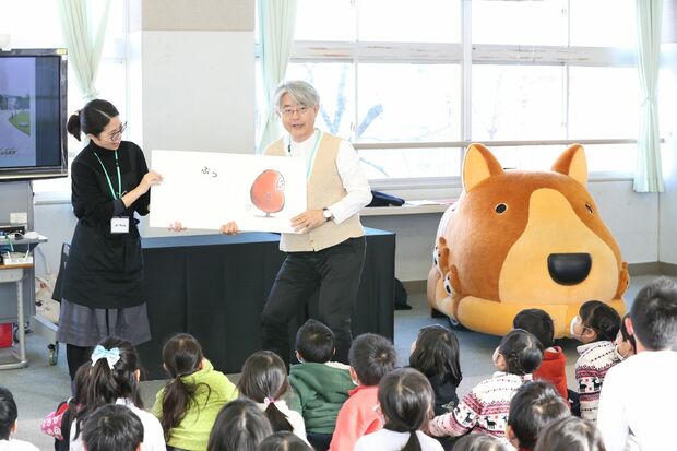 吉成館長の絵本読み聞かせ。身振り手振りで子どもたちを夢中にさせ、楽しませる。右横にあるのが、わんこカート『きらら』