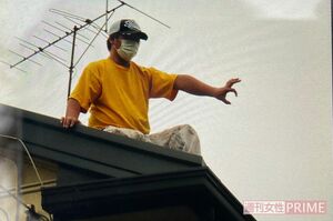 屋根に上がった業者は隙間を見つけ、これくらいの太さのヘビならば通れると指でサイズを示した＝22日午後4時半すぎ