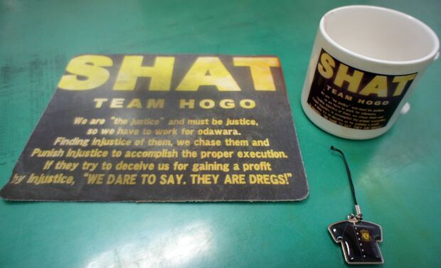 2013年、携帯ストラップ（右手前）を4個作製。2014年、マグカップ（右奥）1個とパソコンのマウスパッド（左）5個を作製。いずれも異動職員への記念品として保護係親睦会幹事が発案した