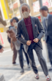 グレーのストライプスーツを着こなして会場に入っていく堺。