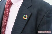 おじさんが襟元につけている“カラフルなドーナツ型バッジ”の正体