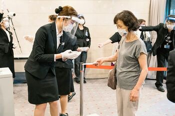 フェイスシールドをつけた係員が、チケットとマスク着用を確認