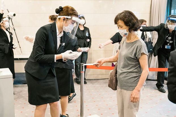 フェイスシールドをつけた係員が、チケットとマスク着用を確認