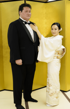 整髪を終え、妻のドルジハンドさんにネクタイを整えてもらう元横綱照ノ富士の伊勢ケ浜親方=31日、東京・両国国技館(写真/共同通信)