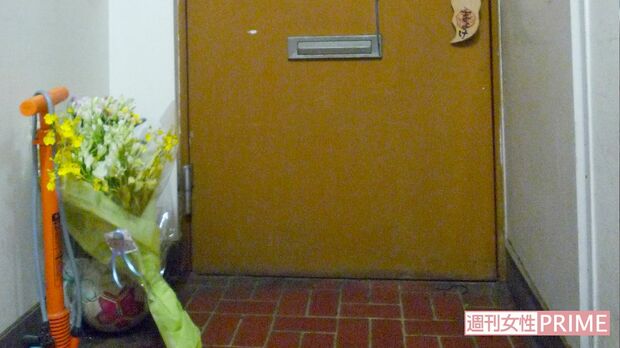 消火活動の生々しい痕跡を残す麻衣さん宅の玄関ドア。玄関先には麻衣さんの死を悼んで花束が手向けられていた
