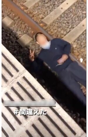 SNSで拡散されている、線路上で寝転ぶ若い男性。ピースサインでおどけるが…