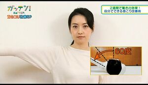 壁に背中をつけて立ち、片腕を上げる