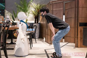 ロボットを遠隔で操縦する人と、店内のスタッフがハイタッチしたり、「お疲れ様」と声をかけ合って働いている　撮影／齋藤周造