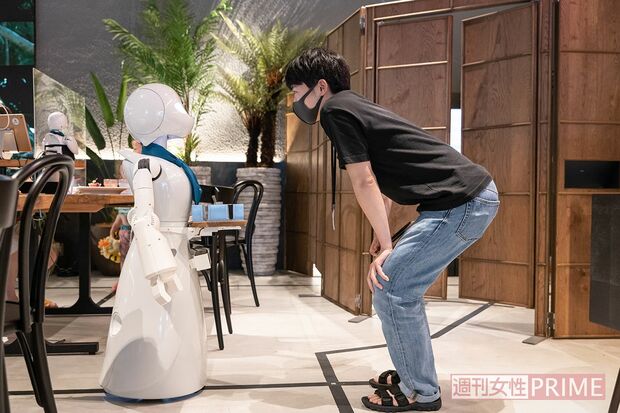 ロボットを遠隔で操縦する人と、店内のスタッフがハイタッチしたり、「お疲れ様」と声をかけ合って働いている　撮影／齋藤周造