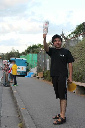 米軍基地の前に立ち、キャンドルを掲げ基地反対を訴える渡具知さん