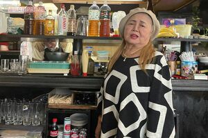 「クイン」の名物ママ“りっちゃん”こと加地律子さん。厨房にいるのは夫の孝道さん。